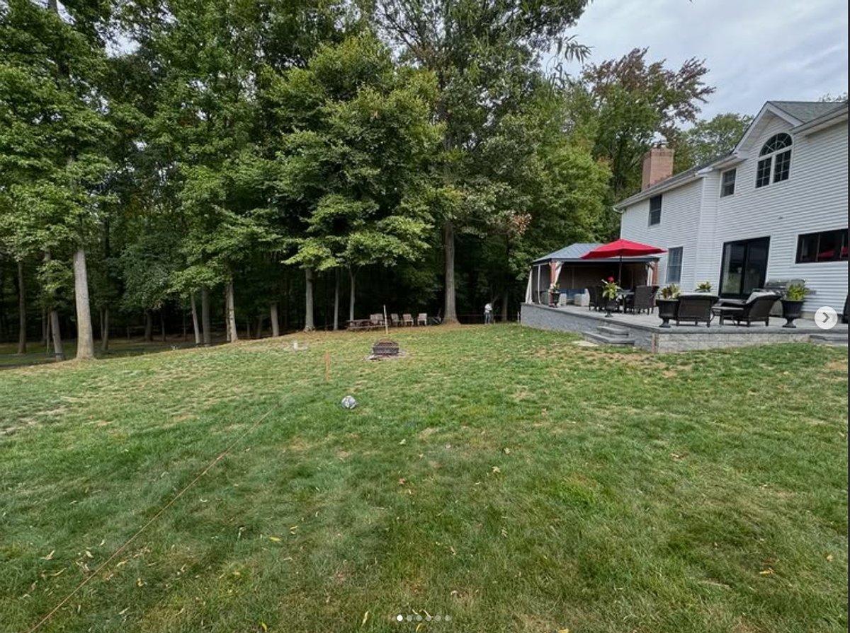 Before — the sloped, uneven backyard with grade stakes set for the plan